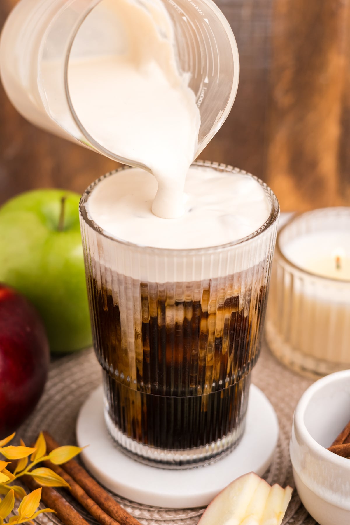 Fresh Apple Crisp Cold Foam being poured over iced coffee.