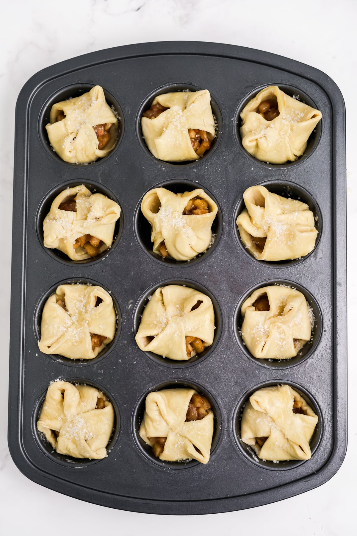 Pastry folded over apple filling brushed with butter and sprinkled with coarse sugar.
