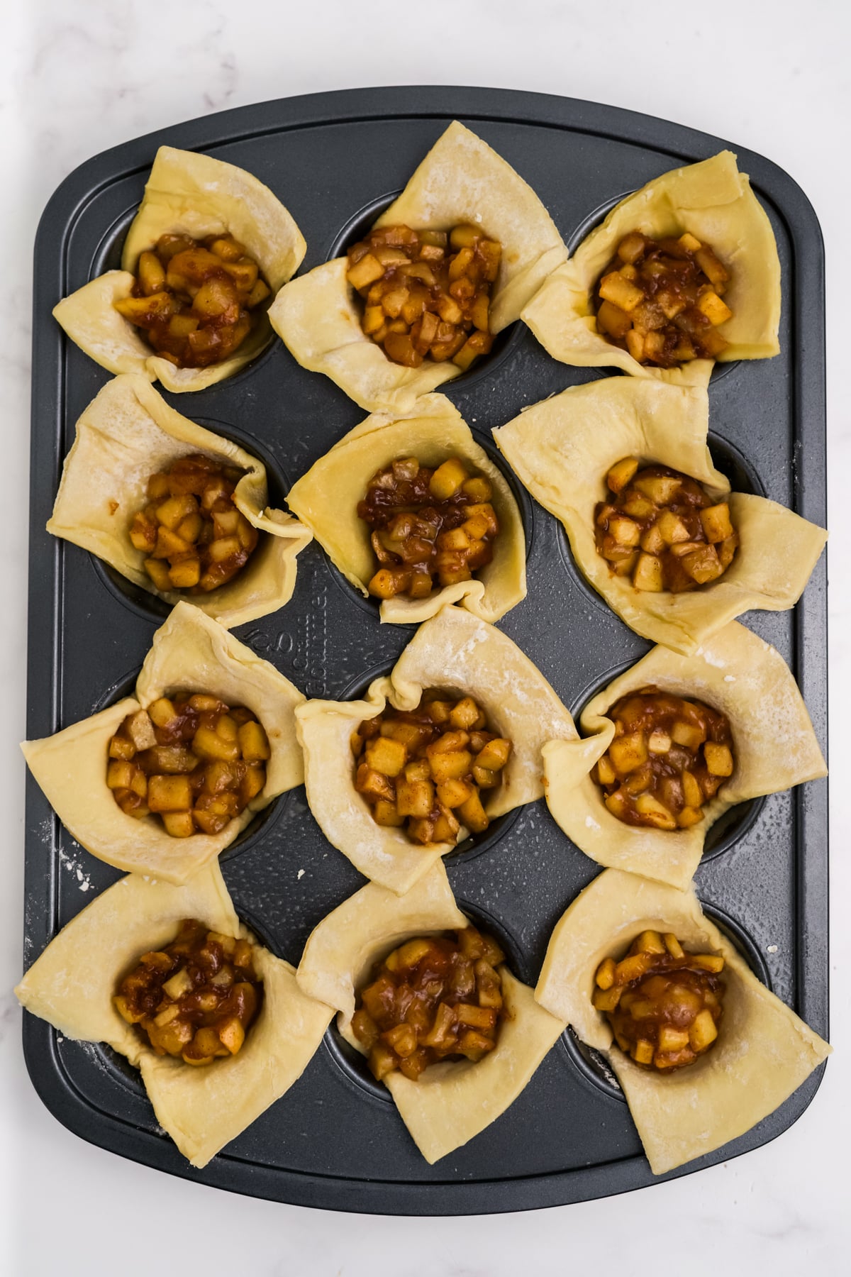 Apple filling added to each pastry cup.