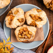 Three Apple Croissants on a plate with the one in front cut in half.