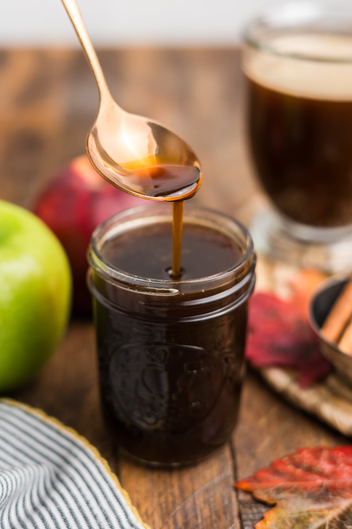 A spoon lifting syrup from a mason jar.
