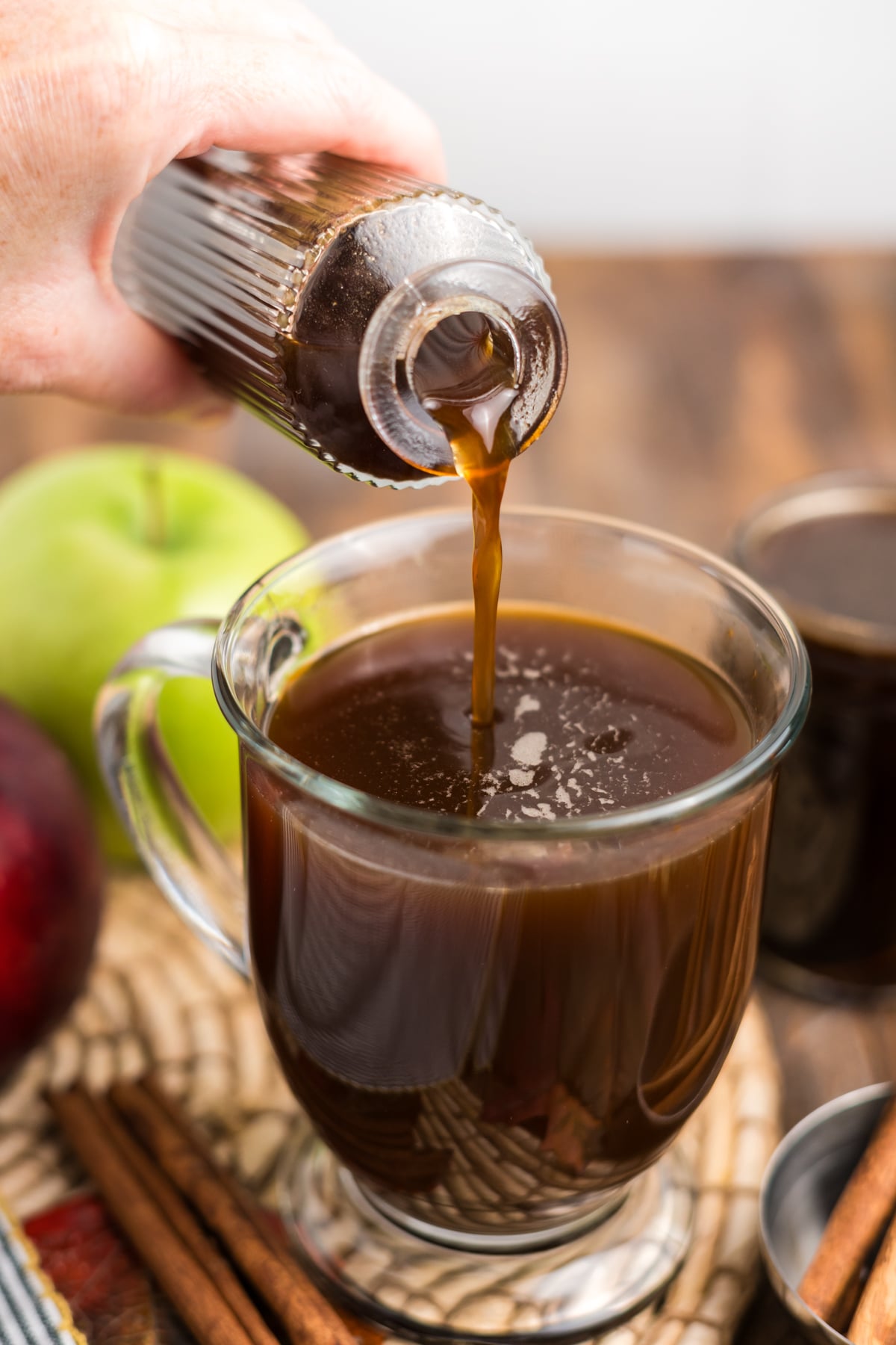 Homemade apple syrup being poured into a cup of coffee.