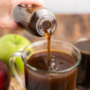 apple syrup being poured into a cup of coffee.
