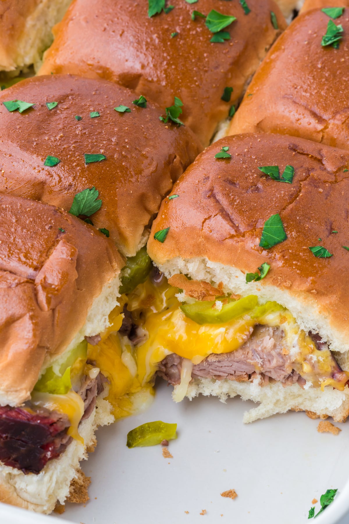 Baked sliders in a baking dish with one slider removed.