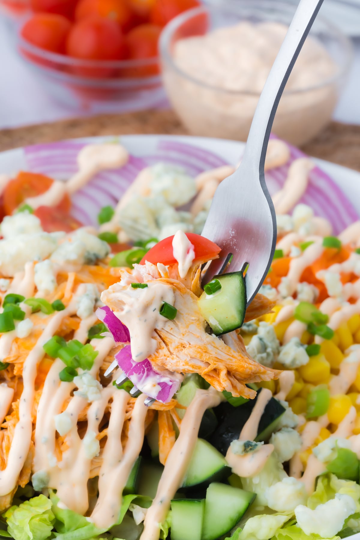 A fork holding a bite of salad above a serving bowl.