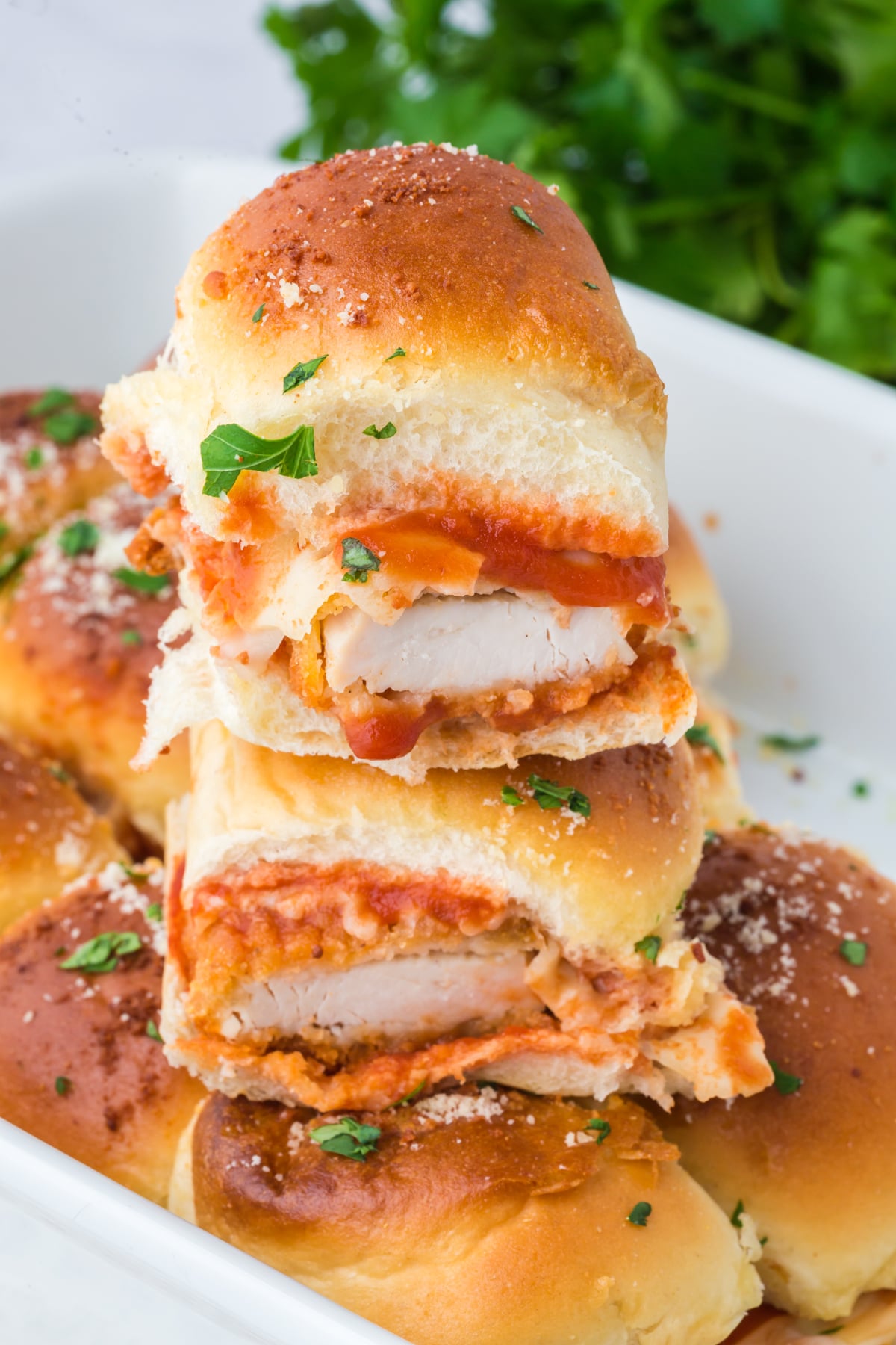 Three sliders stacked on one another in casserole dish.