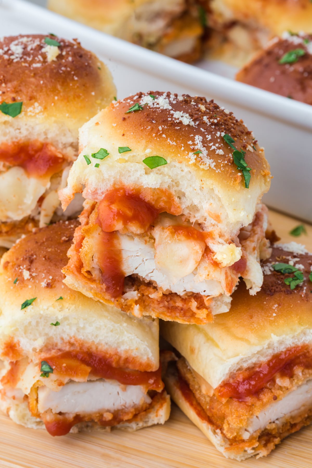 A pile of Chicken Parmesan Sliders on cutting board.