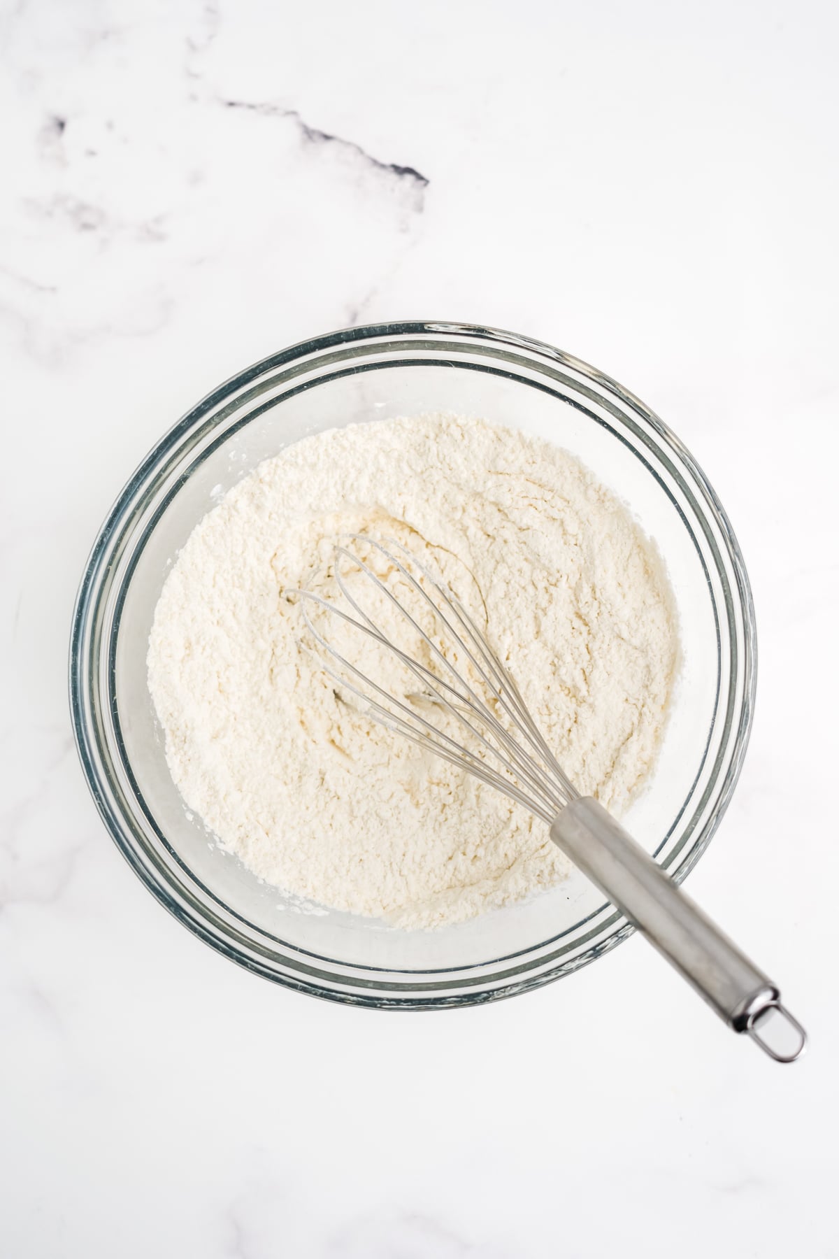 The dry ingredients in a bowl with a whisk.