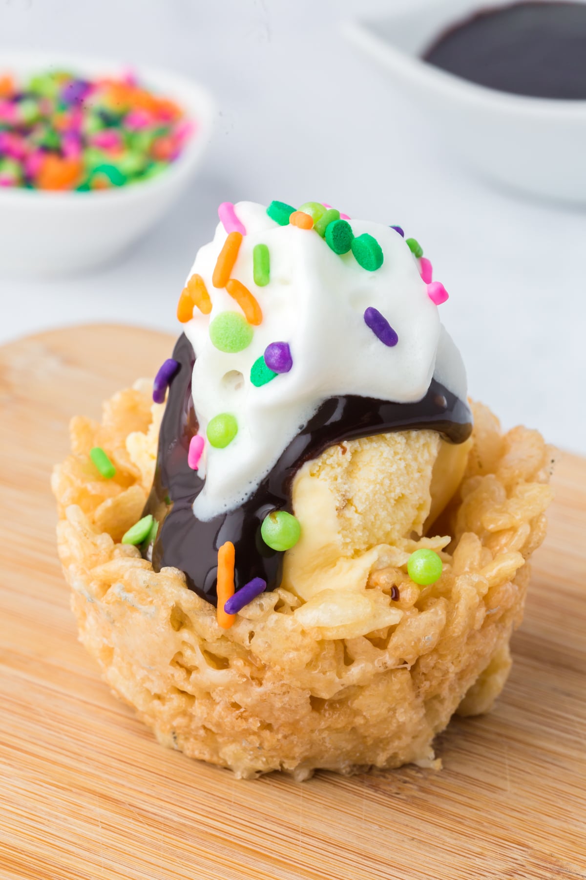 Ice cream bowl topped with hot fudge, whipped topping and sprinkles.