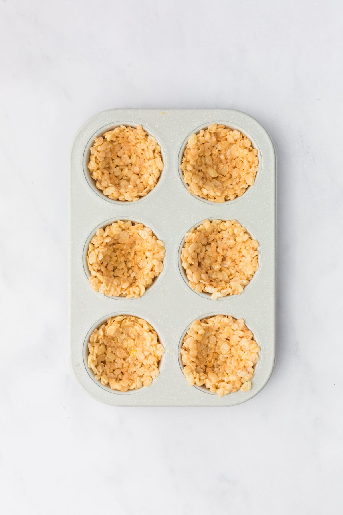 Rice Krispie mixture pressed into bowls in muffin pan. 