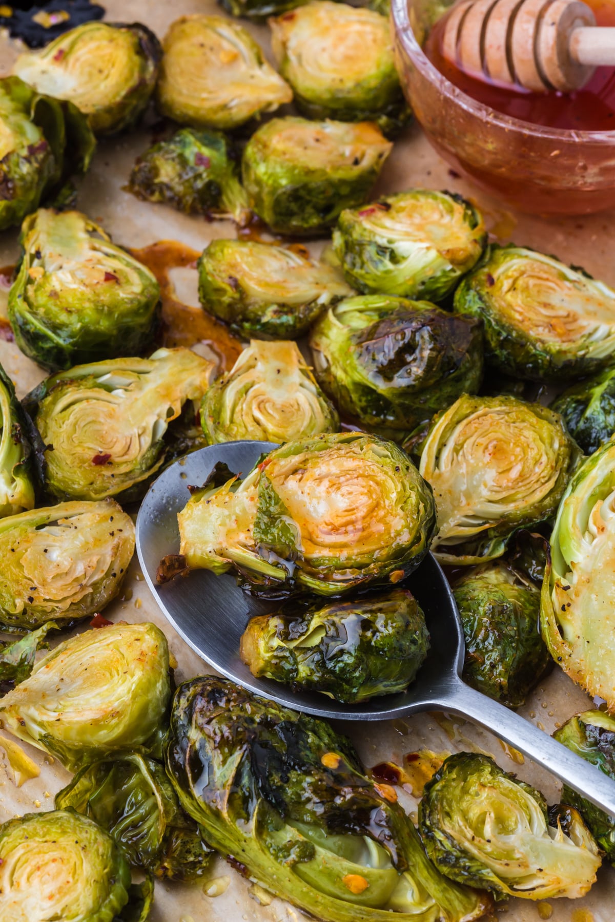 A spoonful of cooked Brussels sprouts lifting off of a baking sheet.