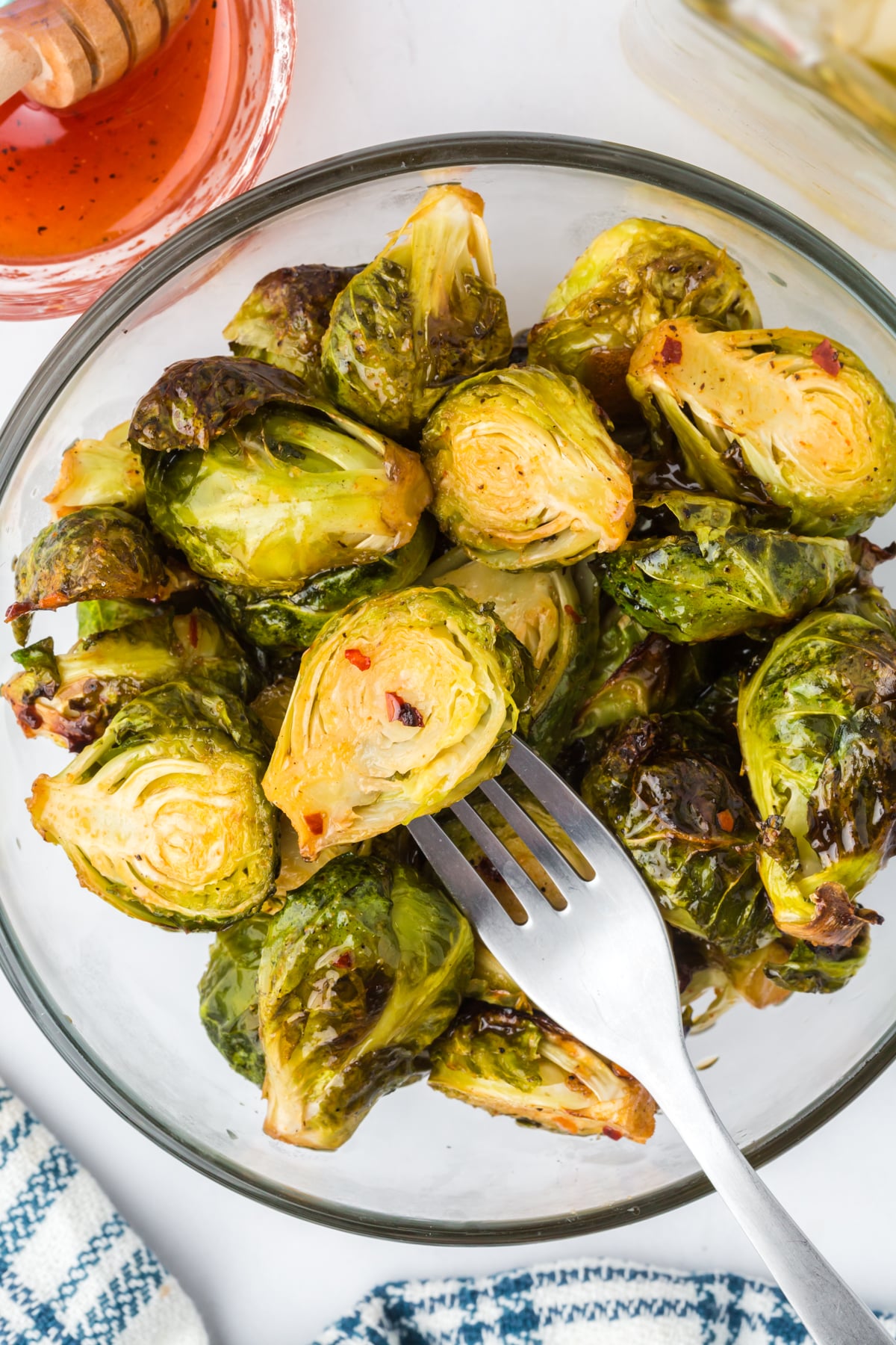 A pile of roasted Brussels Sprouts in a serving bowl with a fork lifting one out.