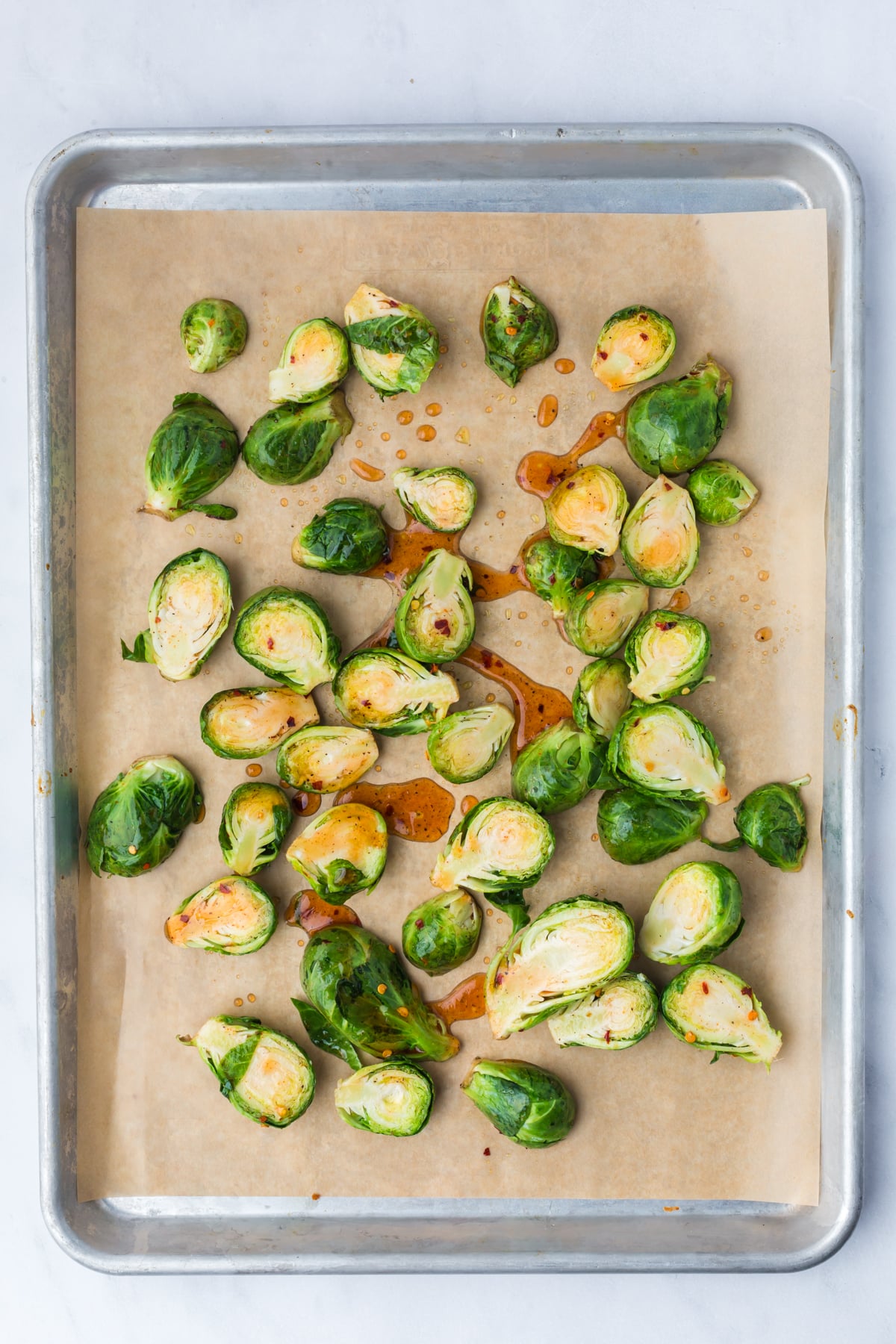Raw Brussels Sprouts on a parchment-lined baking sheet.