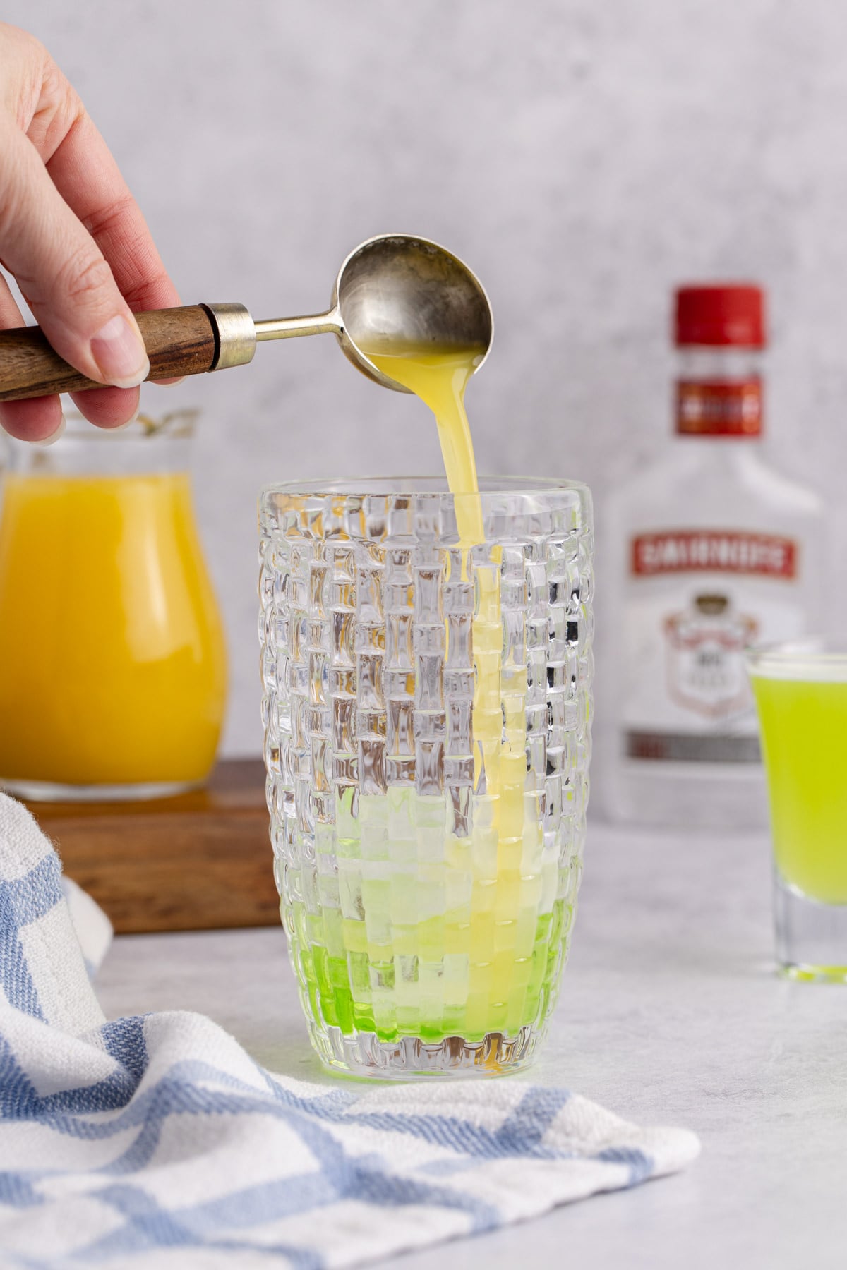 Pineapple juice being added to filled cocktail shaker.