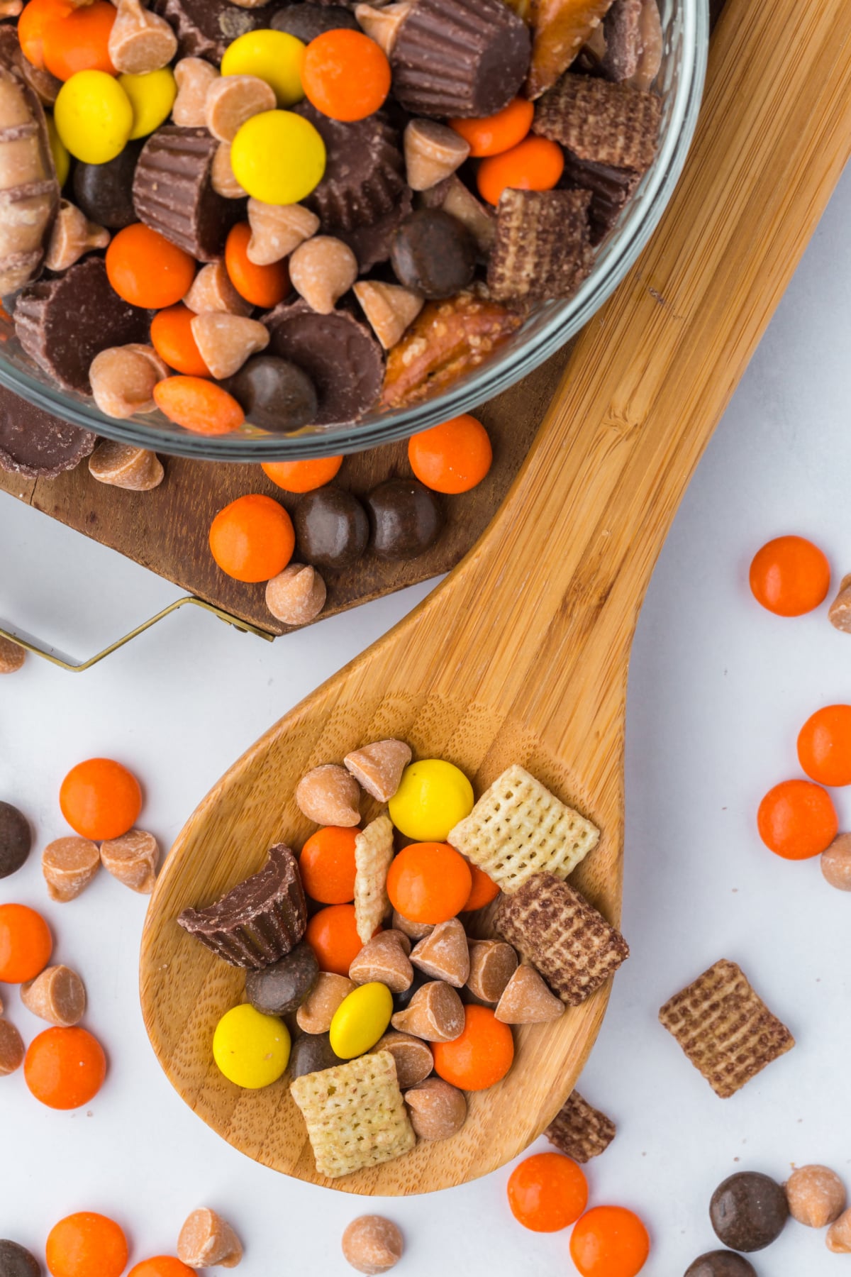 A spoonful of trail mix beside a bowl filled with the sweet and salty snack mix.