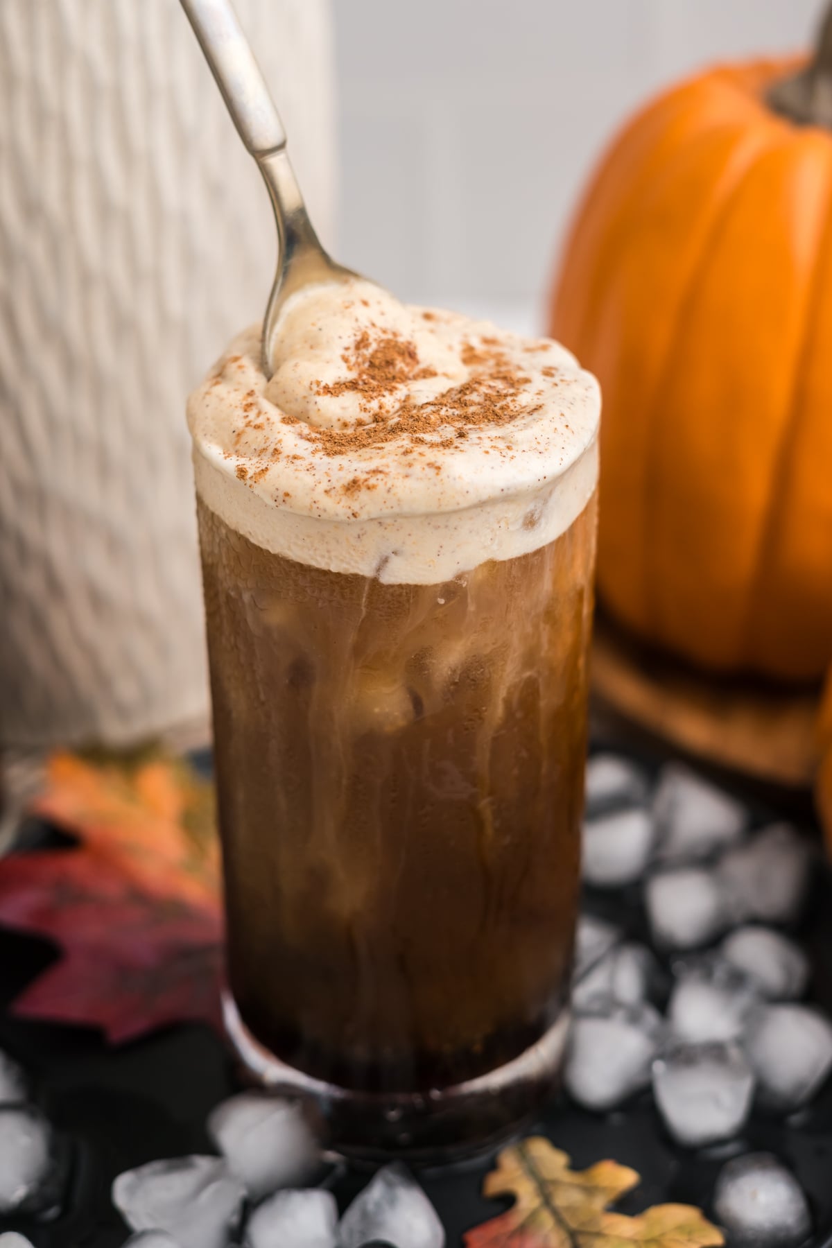 Spoon dipping into creamy pumpkin cold foam on a cold brew.