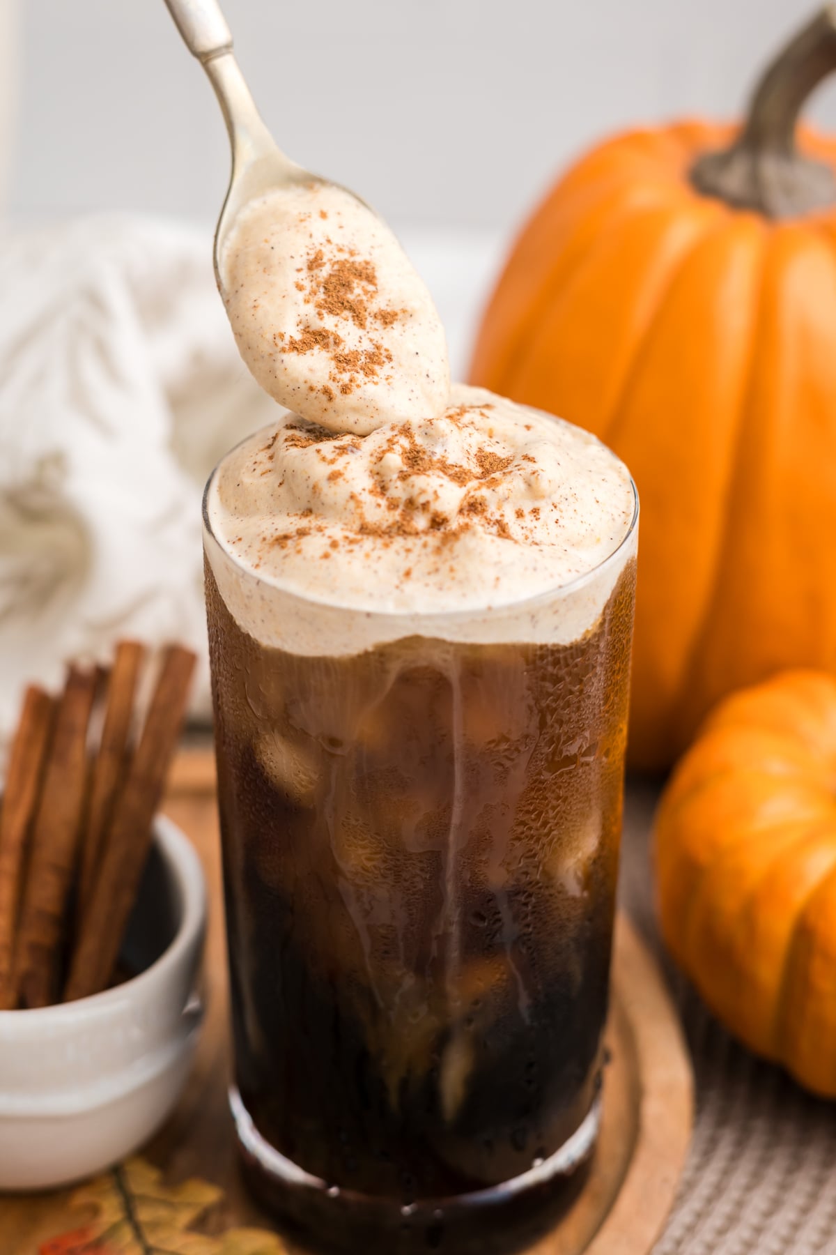 A spoonful of pumpkin cold foam above the cold brew.