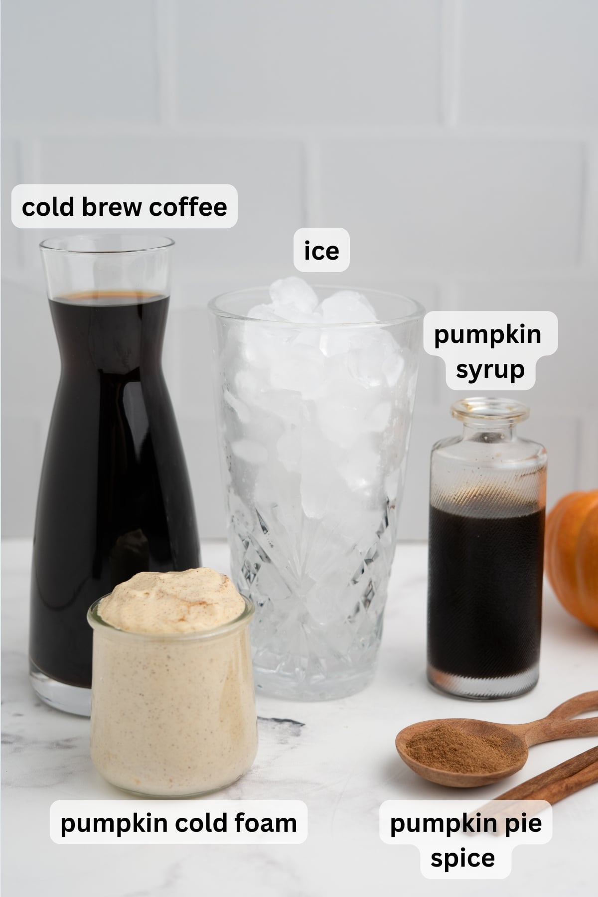 All of the ingredients needed to make a  Pumpkin Cream Cold Brew in glasses on a table.
