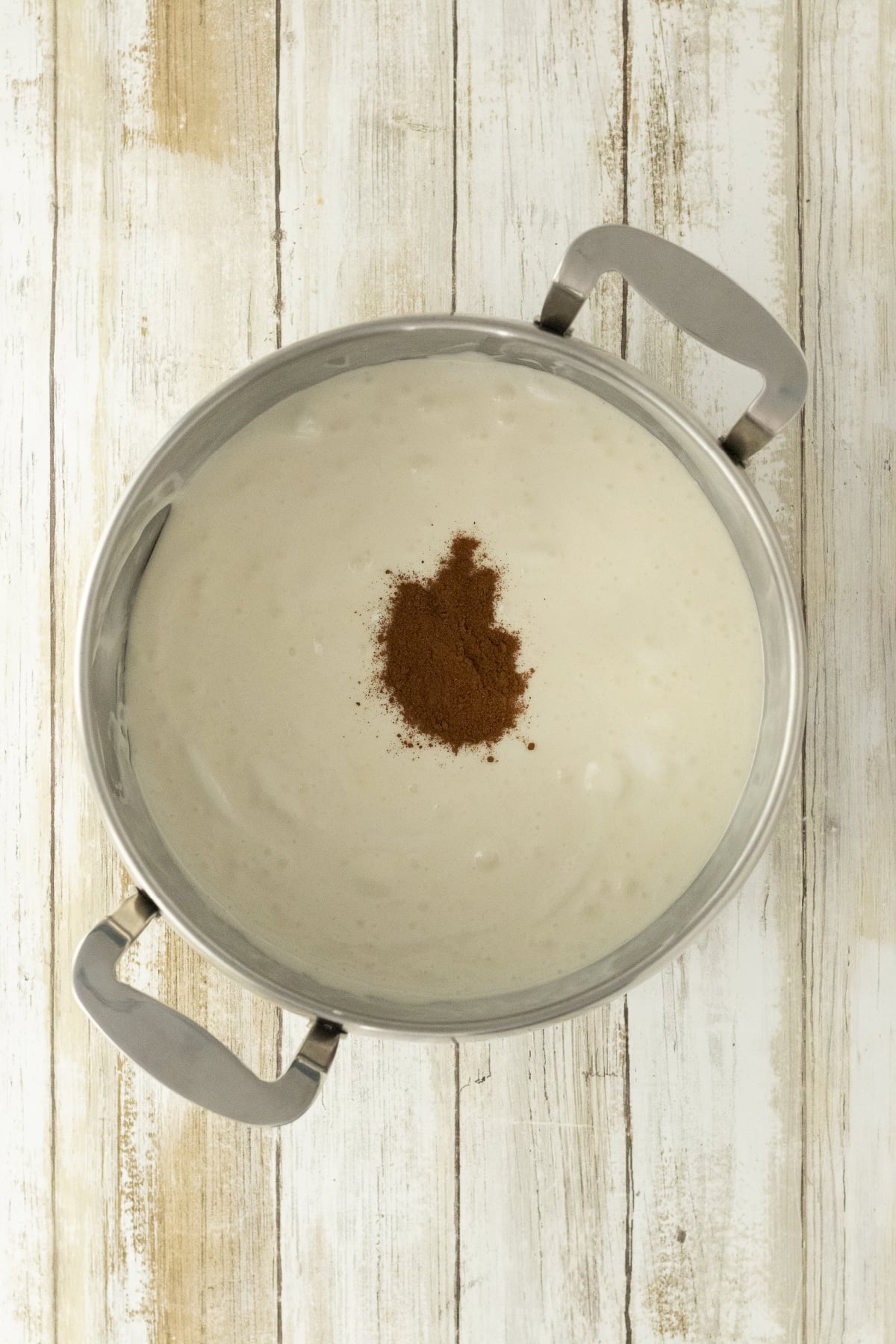Pumpkin pie spice added to melted marshmallow mixture in saucepan.