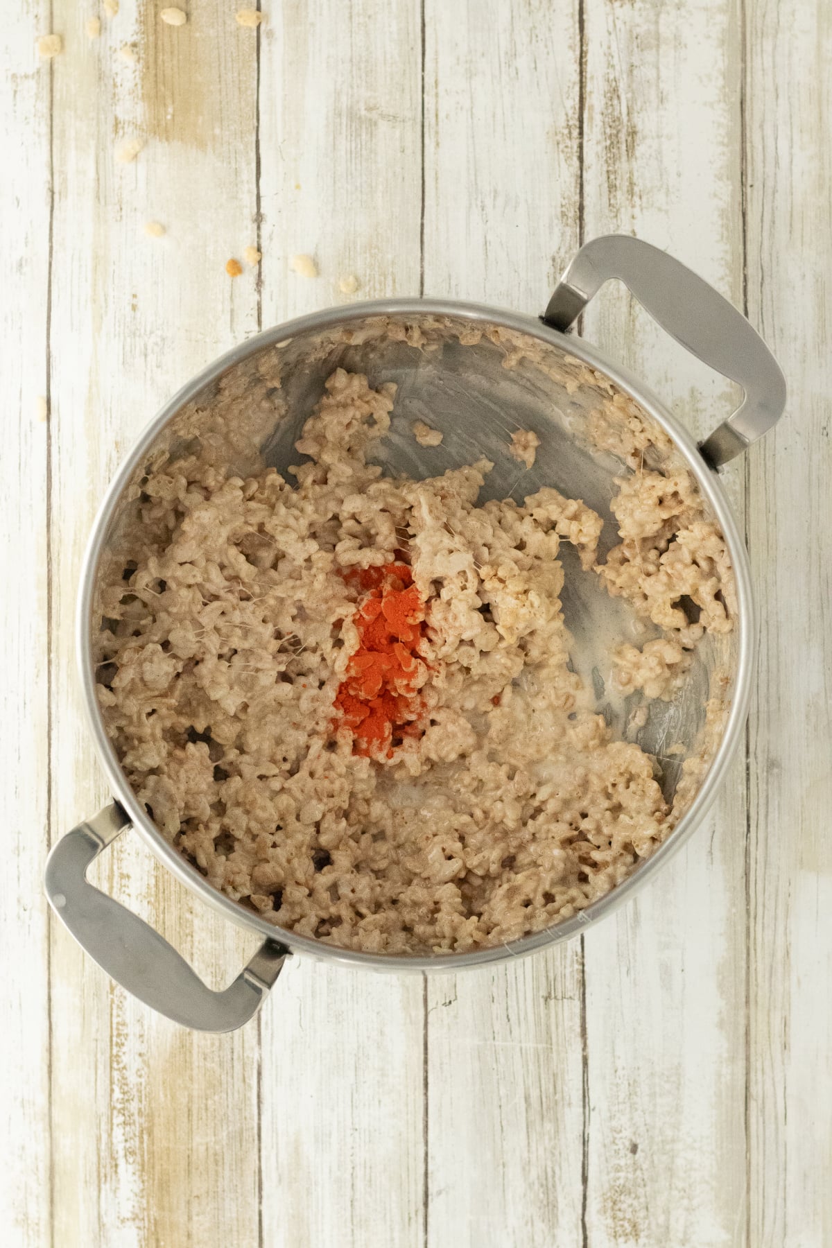 Remaining cereal mixture with orange food coloring added in saucepan.