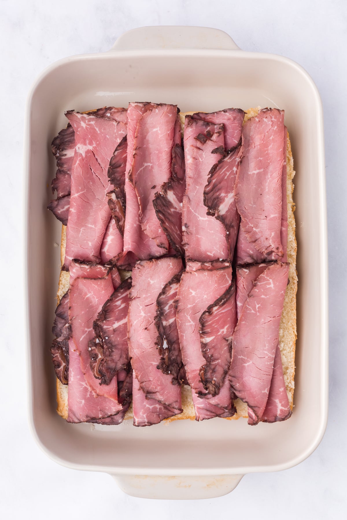 Baked slider bottom covered with cheese and sliced roast beef.
