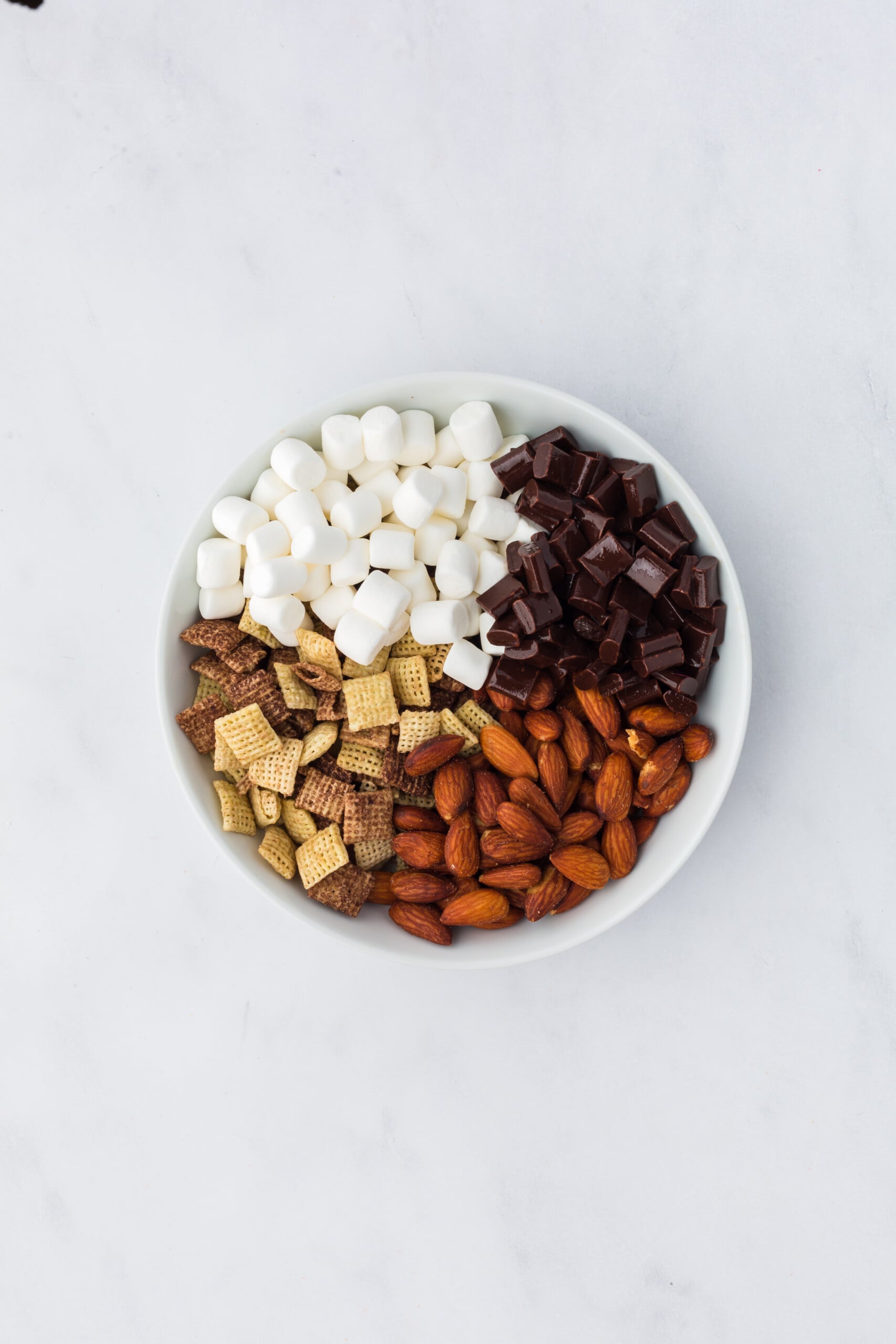 Chocolate Chex cereal, mini marshmallows, roasted salted almonds, and semi-sweet chocolate chunks in a large mixing bowl