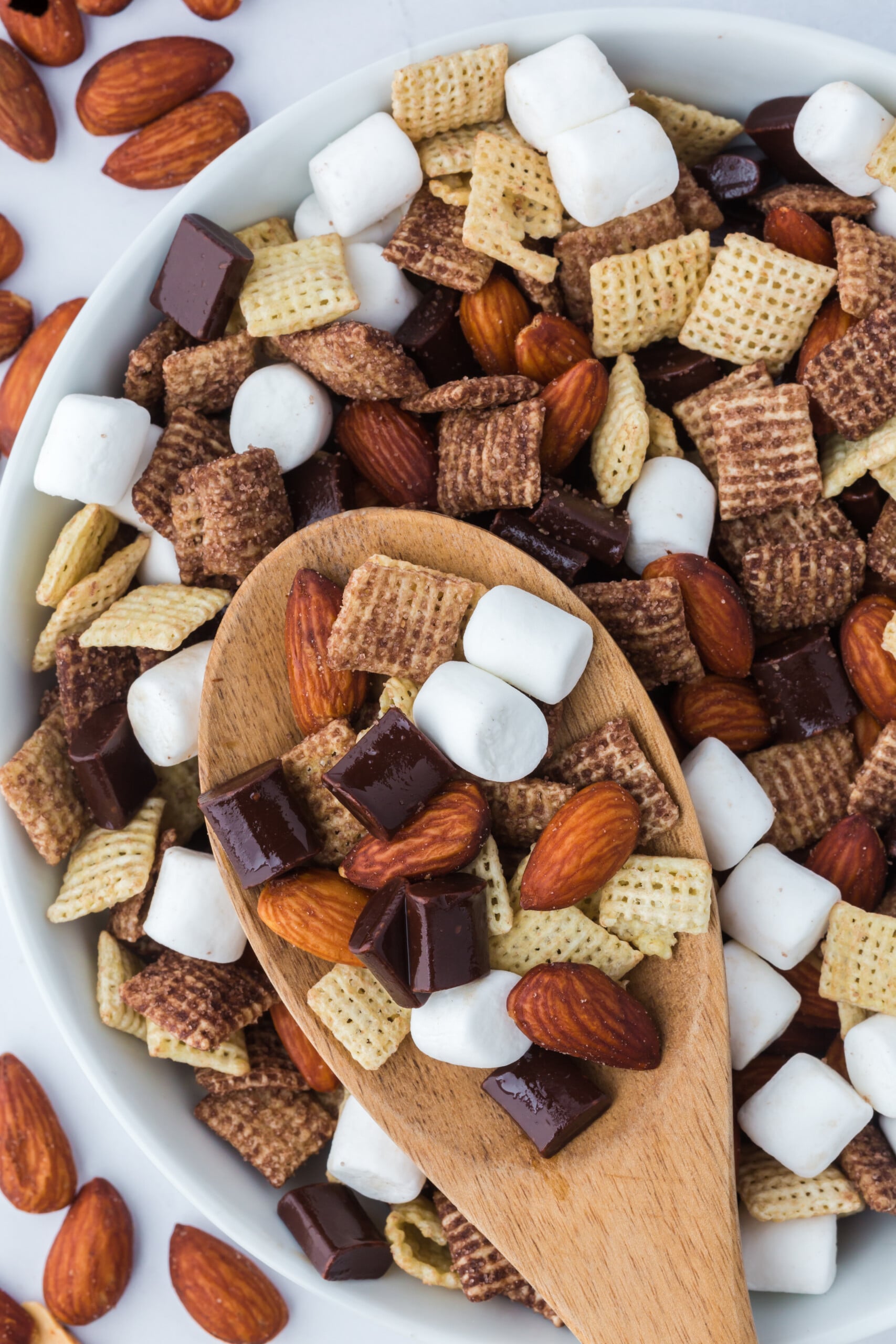 A wooden spoonful of trail mix on top of a bowlful.