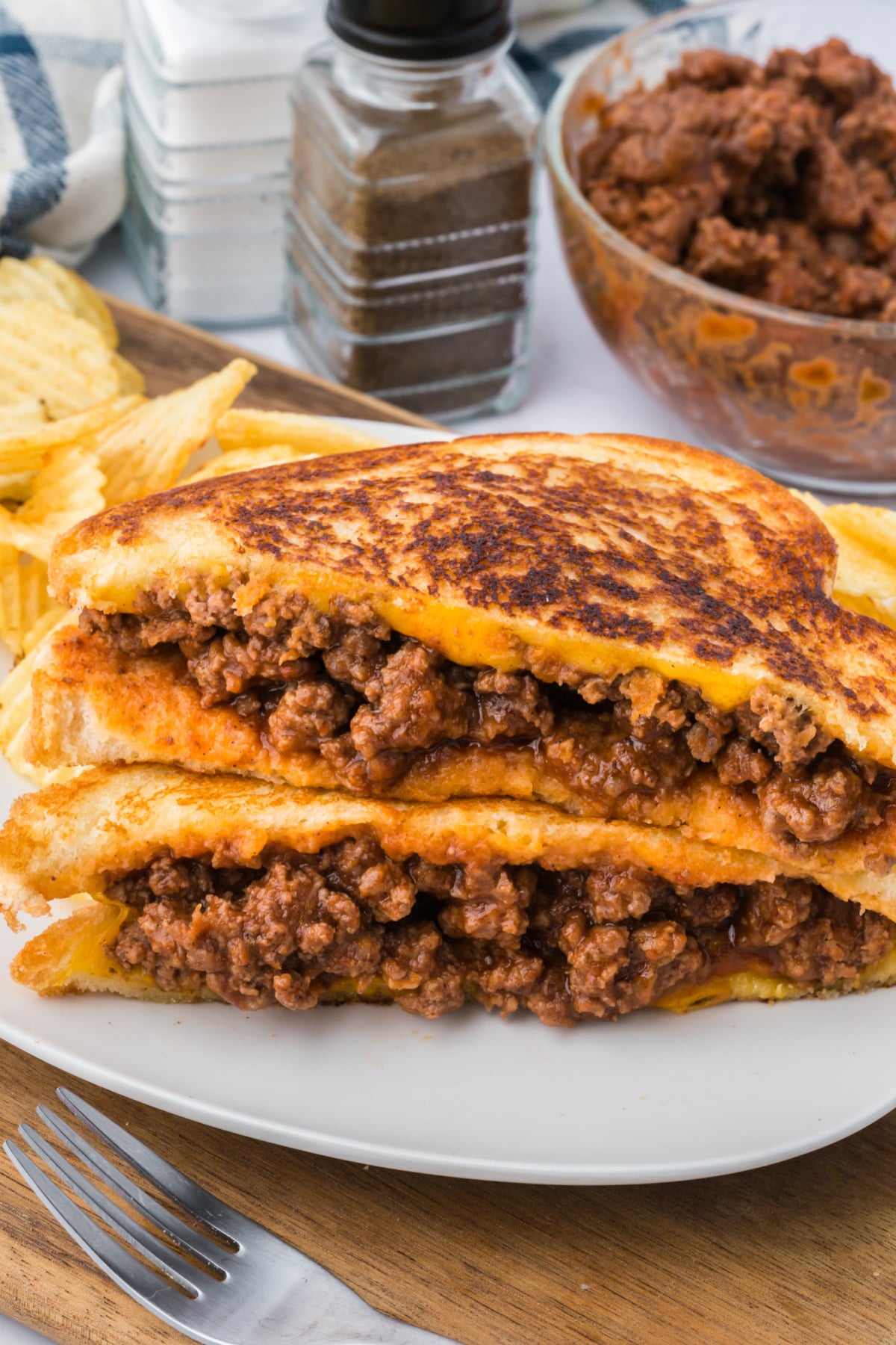 Two sloppy joe grilled cheese halves on top of each other on a plate.
