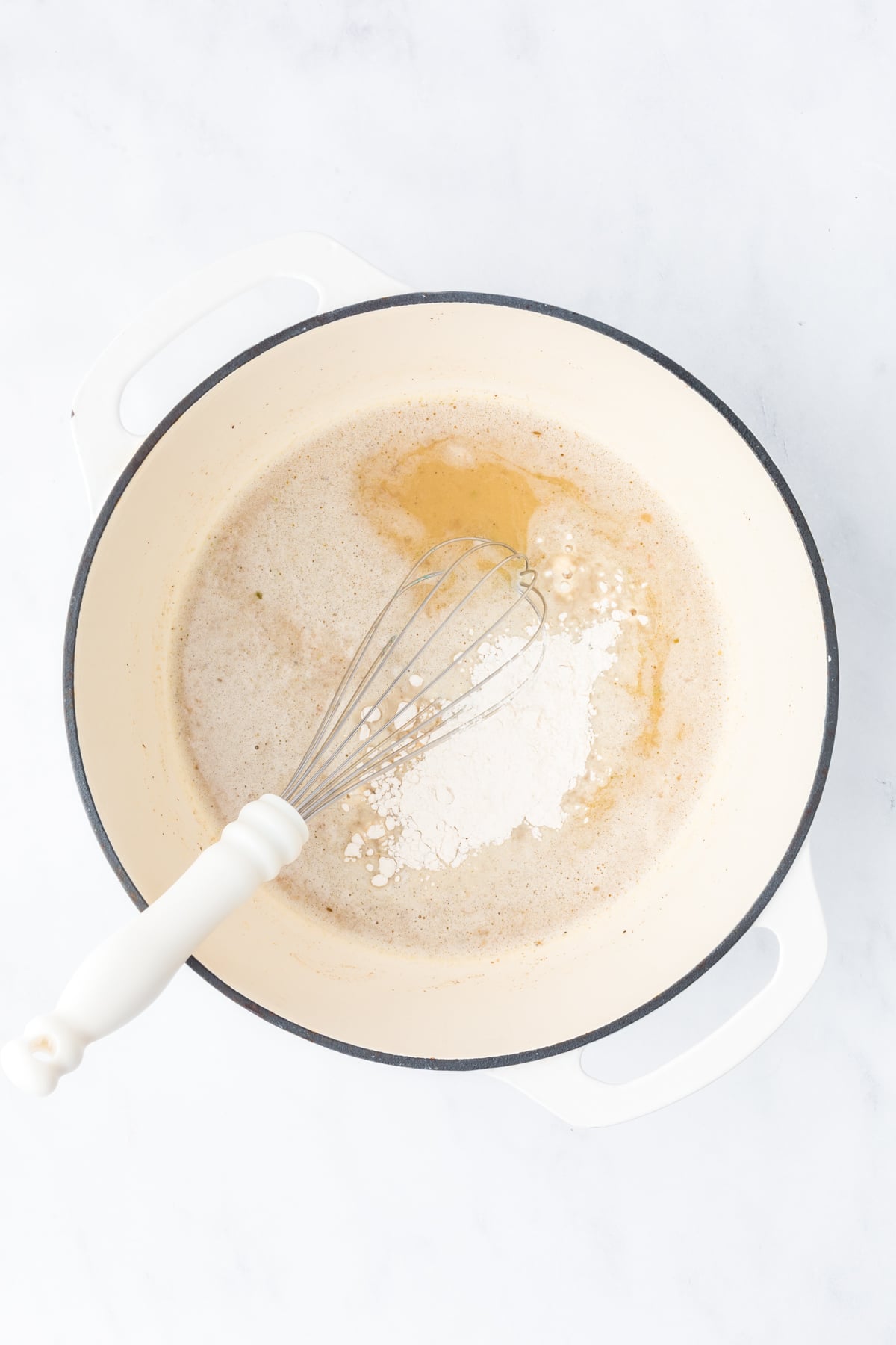 Whisking turkey broth into the roux to make gravy.
