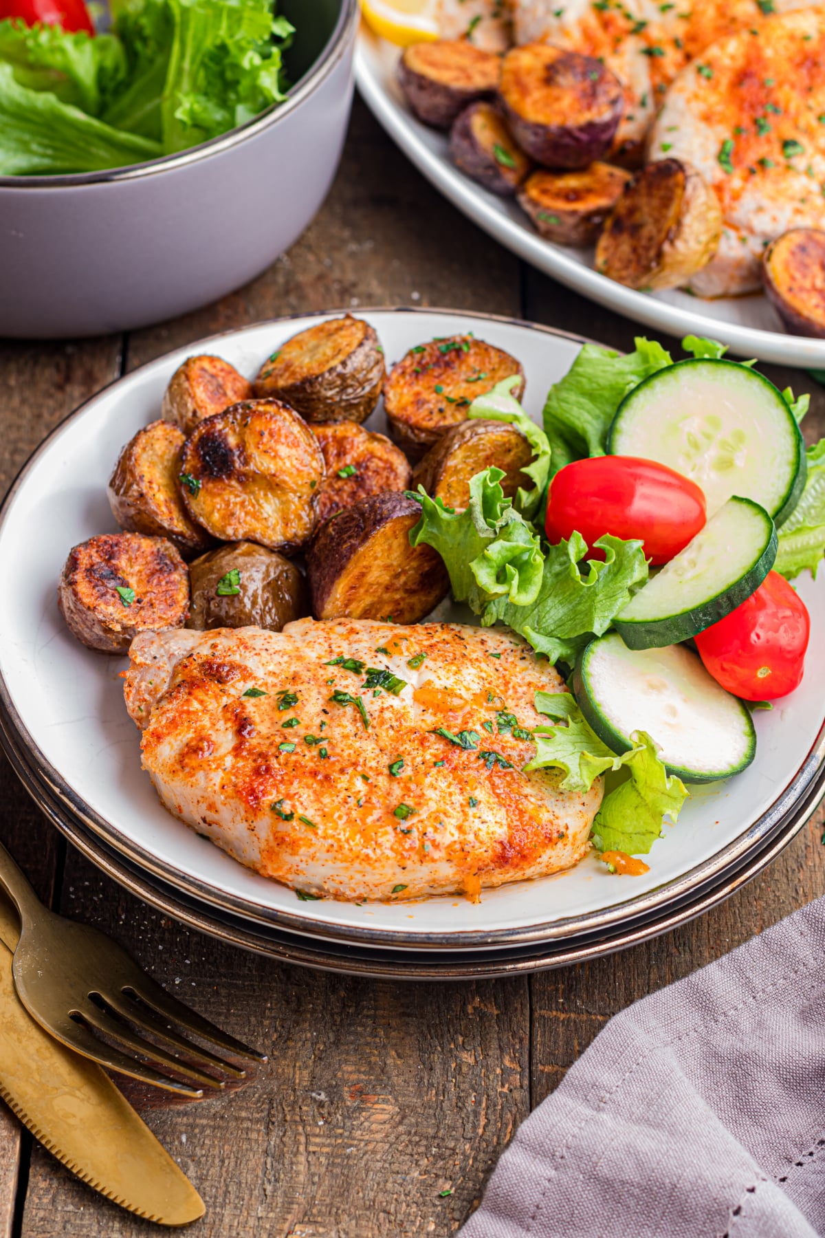 A plate with pork chops, potatoes and a salad.