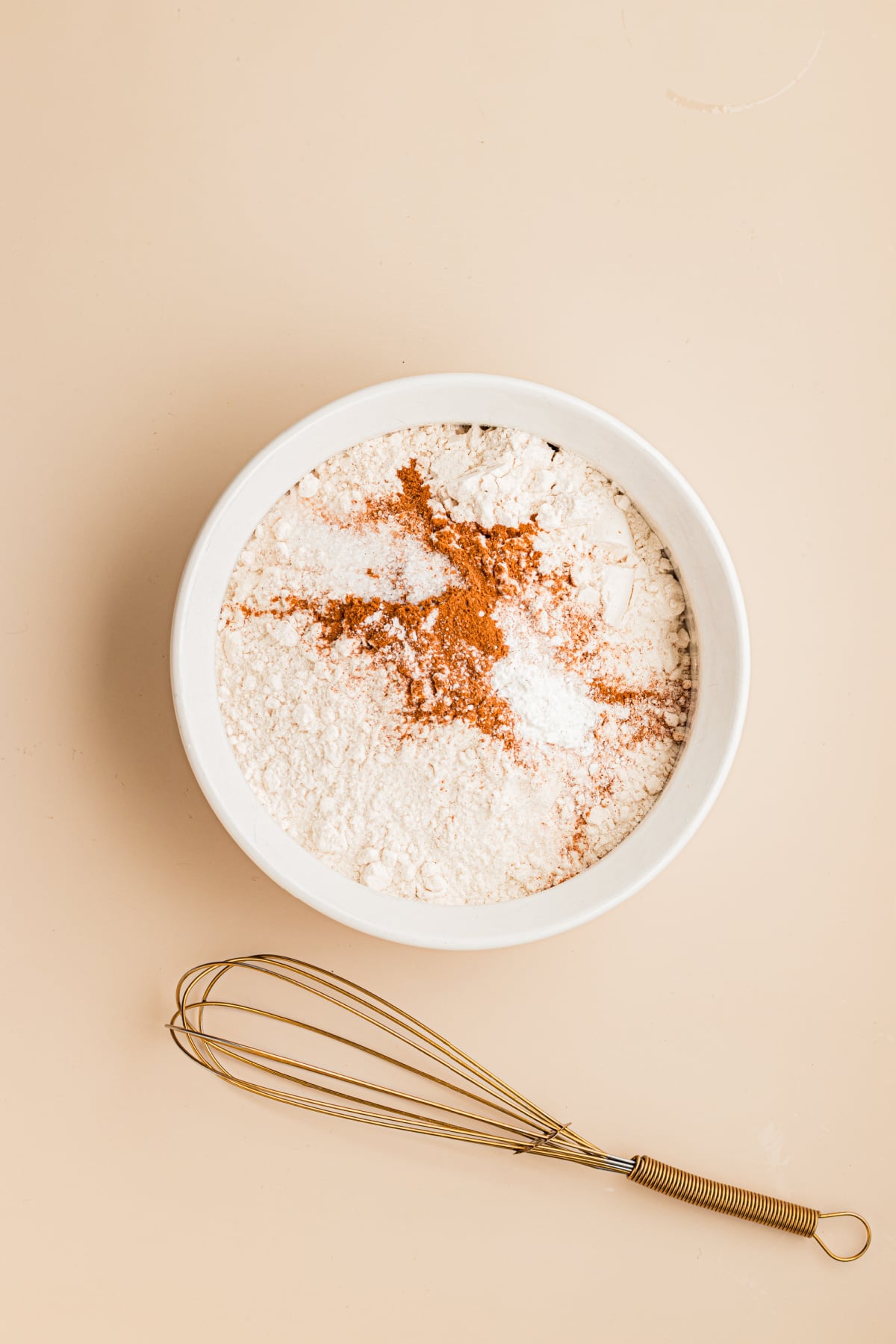 All of the dry ingredients needed to make recipe in a bowl with a whisk.
