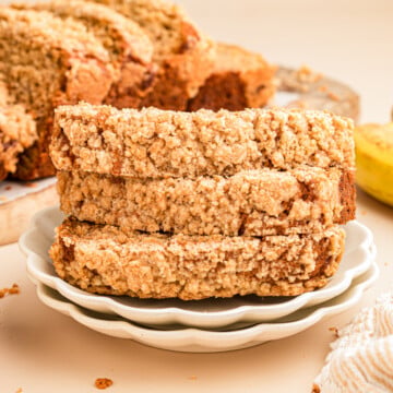 A stack of three slices of banana bread with streusel topping on a plate.