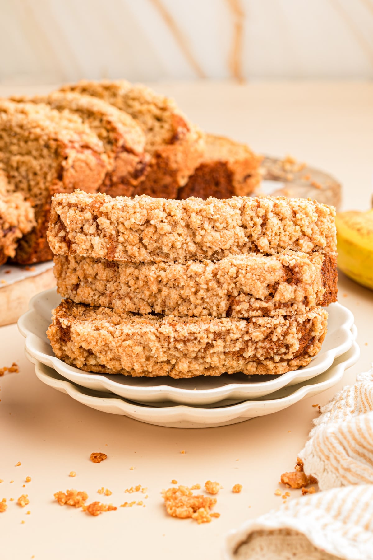 A stack of three slices of banana bread with streusel topping on a plate.