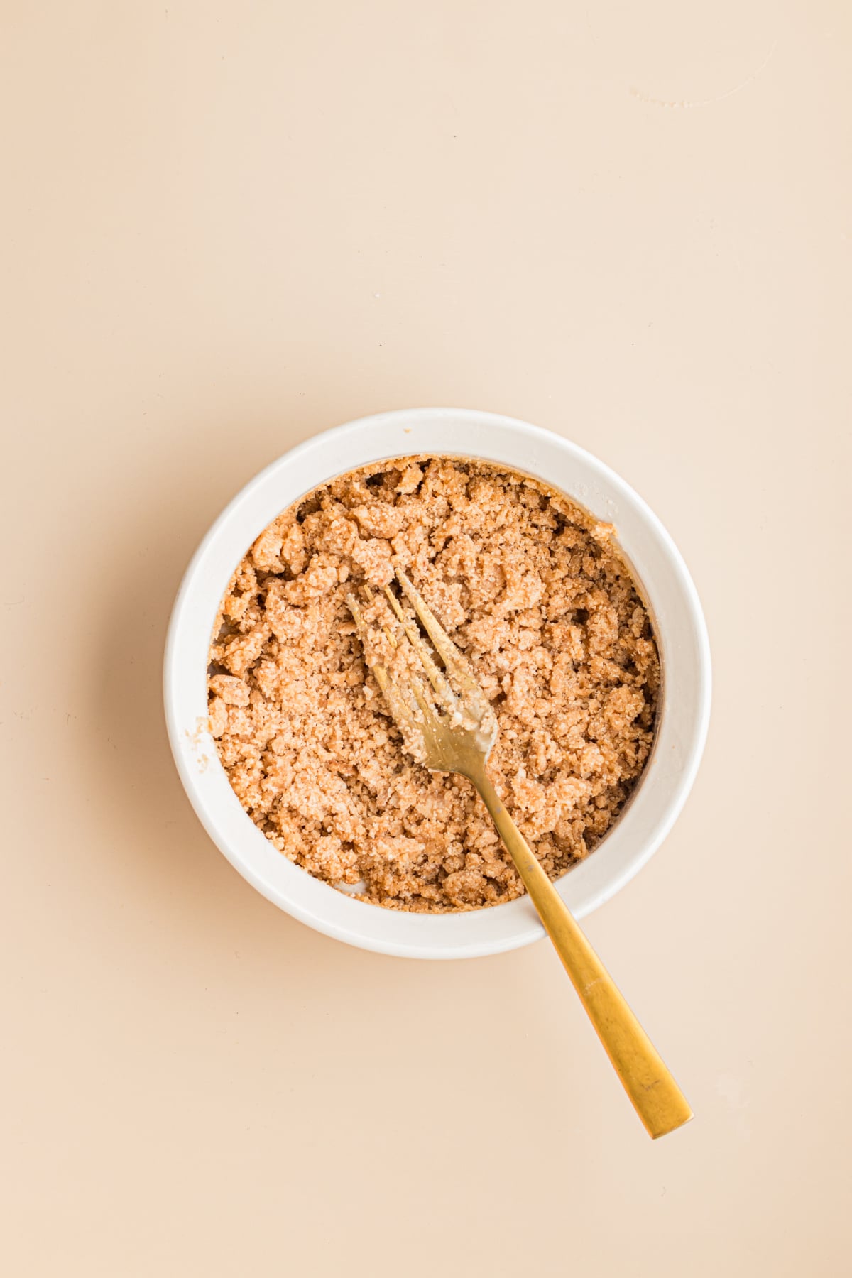 Streusel ingredients with whisk mixed together in bowl on table.