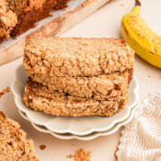 A stack of three slices of banana bread with streusel topping on a plate.