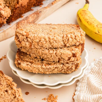 A stack of three slices of banana bread with streusel topping on a plate.