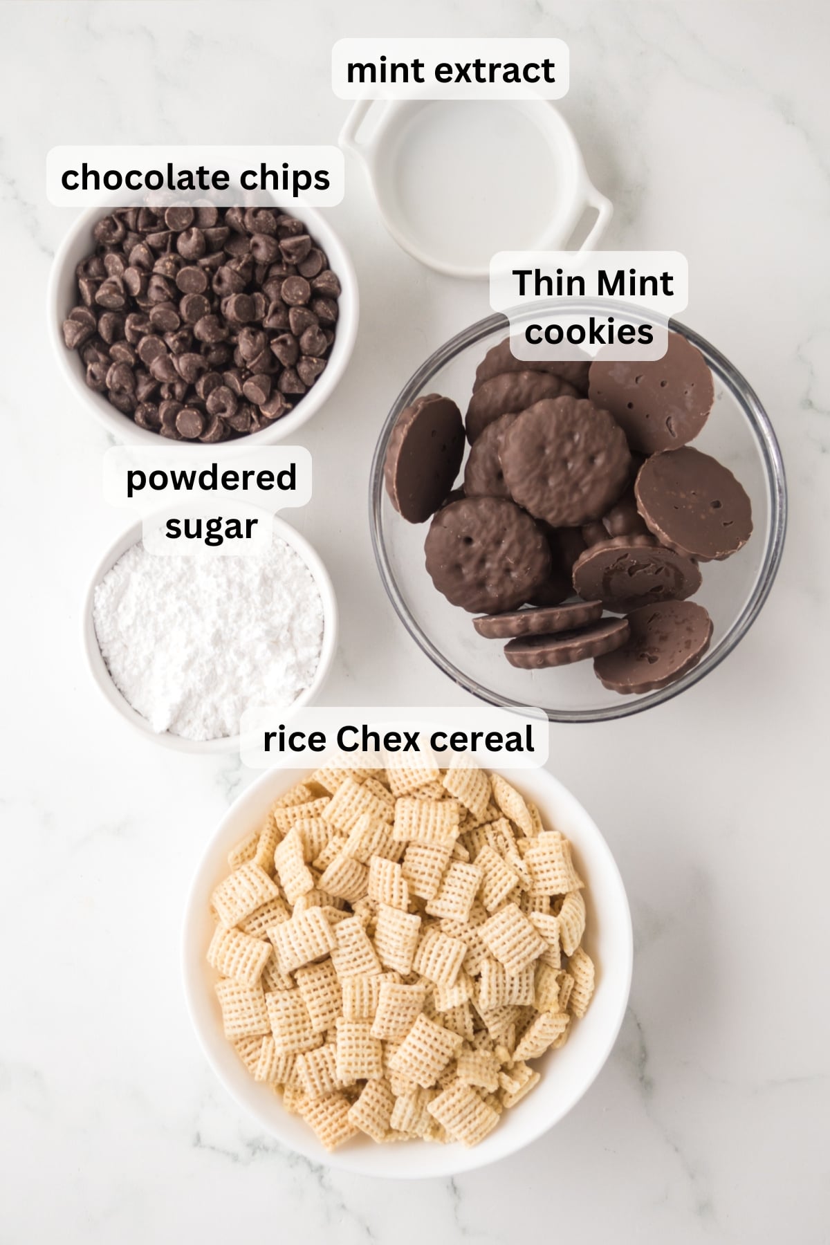 All of the ingredients needed to make mint muddy buddies in bowls on a table.