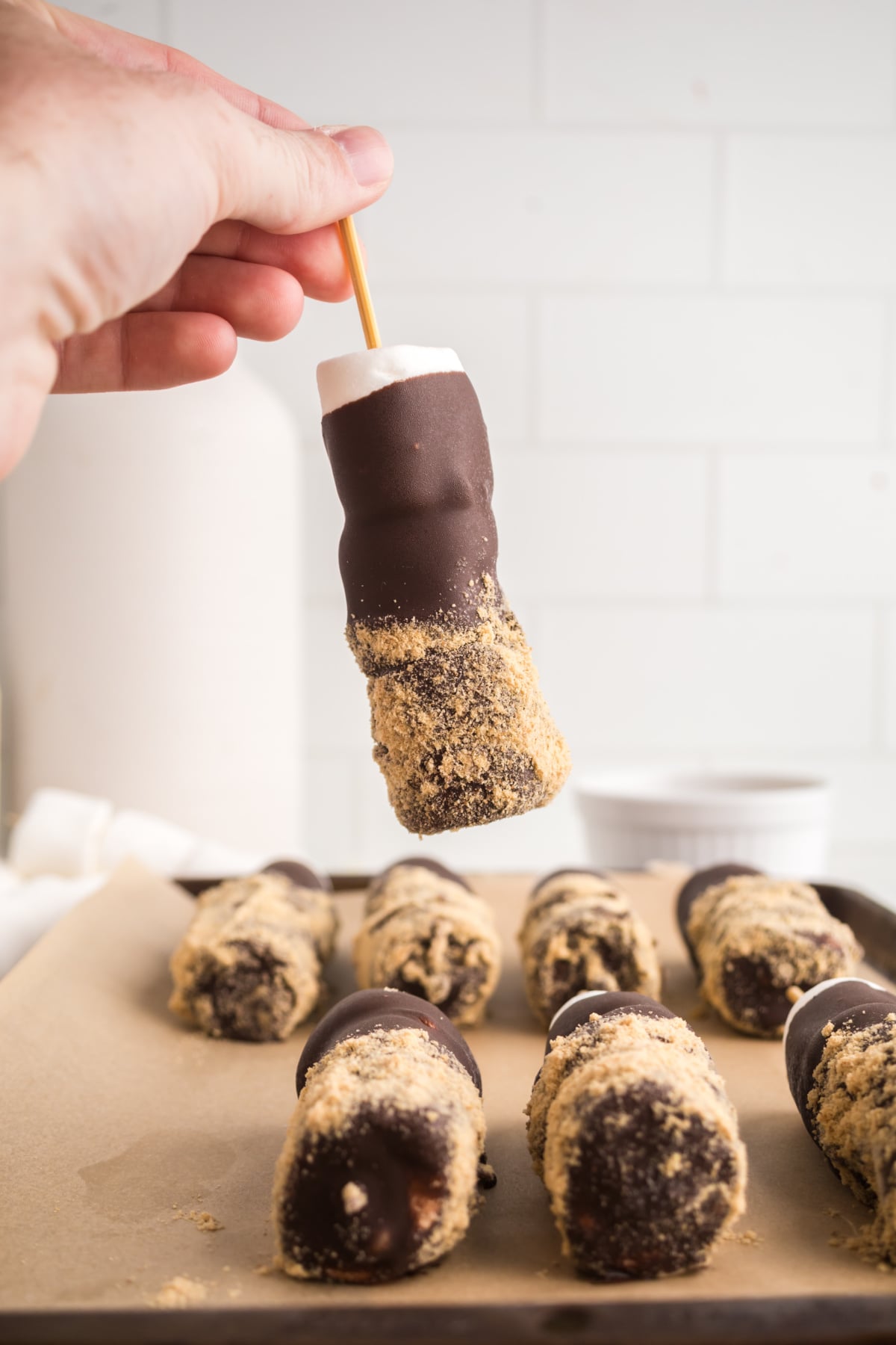 Chilled skewers on a parchment covered baking sheet with one held in the air.