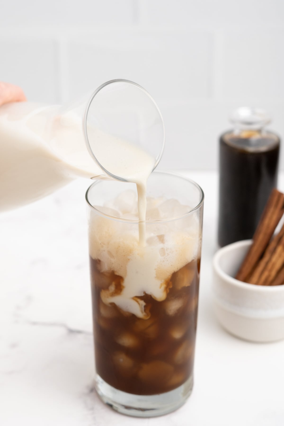 Oat milk added to shaken espresso in ice filled glass.