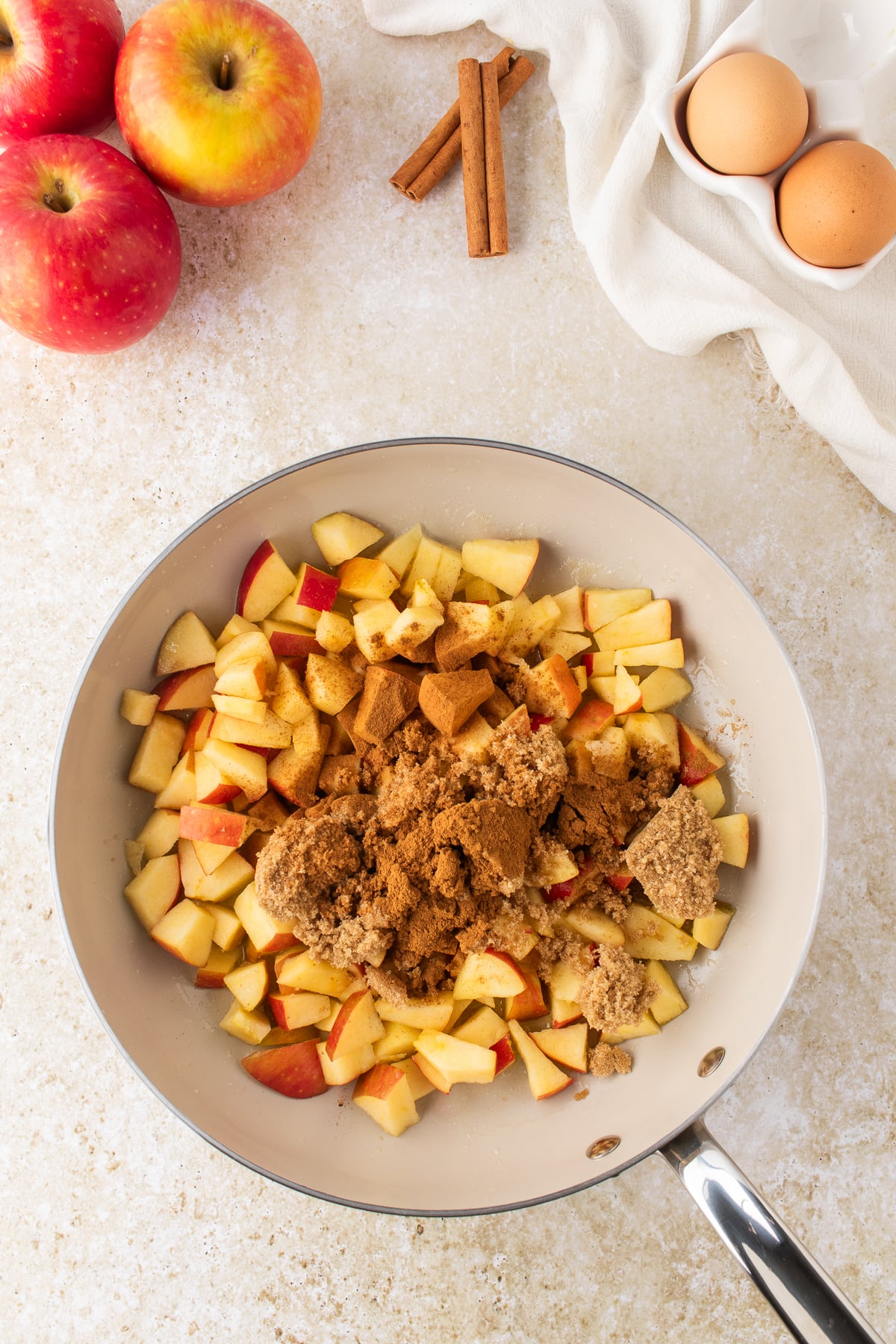 Diced apples cooking with butter, brown sugar, and cinnamon in a skillet.