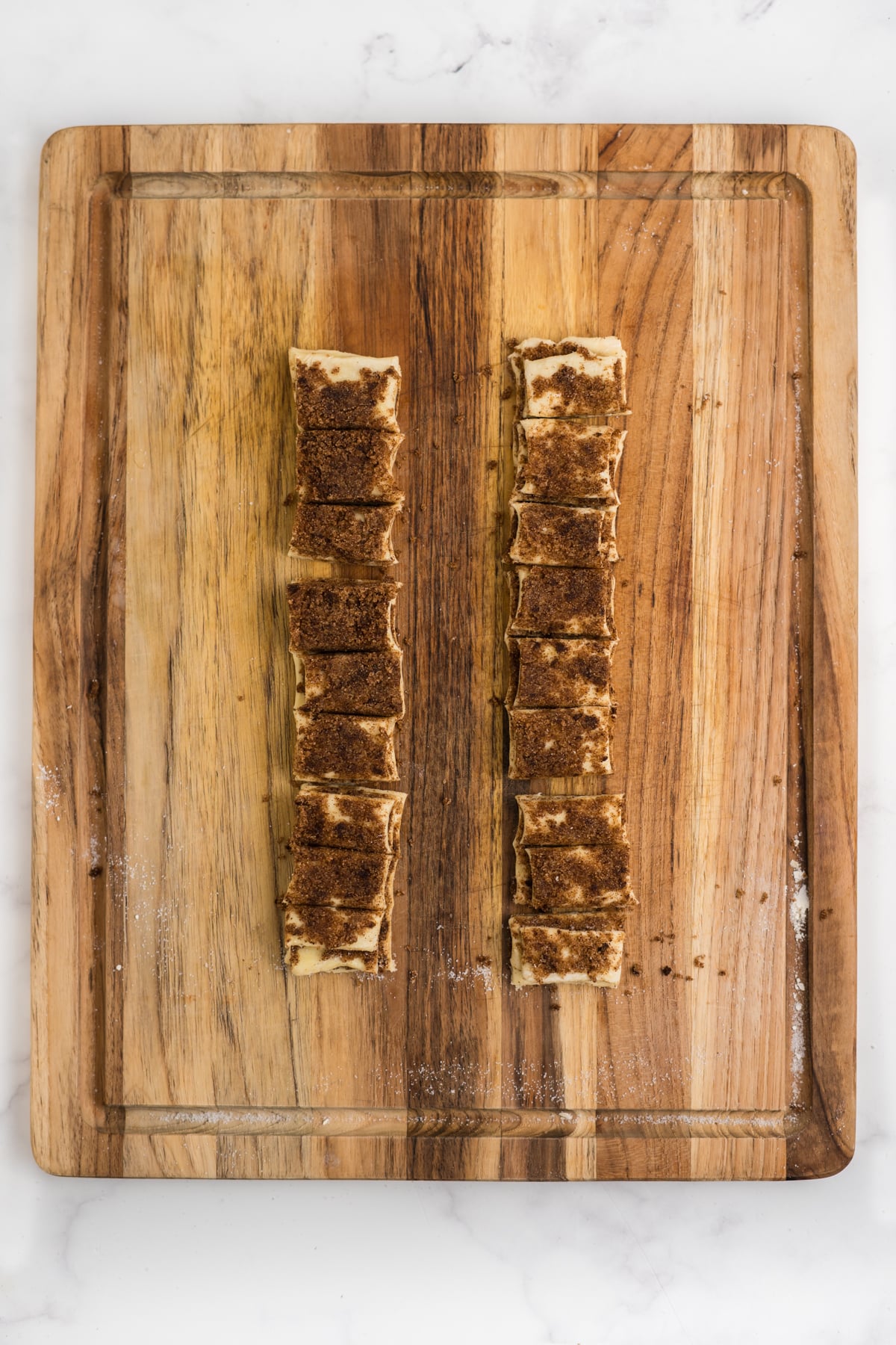 Cinnamon-filled puff pastry cut and stacked into layered pieces on cutting board.