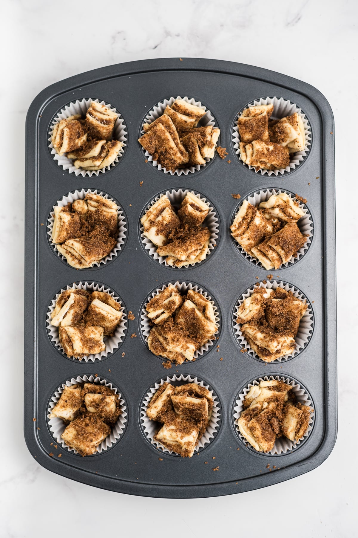 Stacked puff pastry pieces arranged upright in parchment-lined muffin cups.