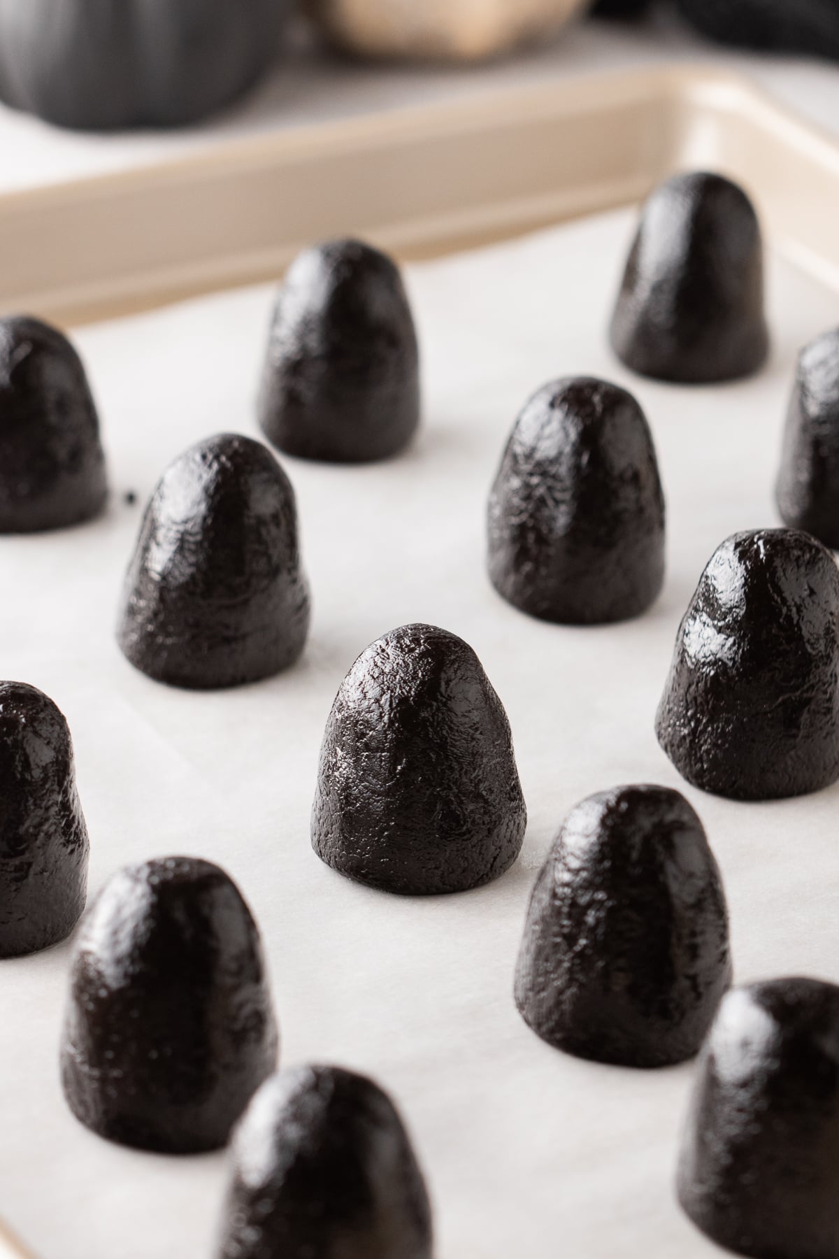 Oreo mixture shaped with a narrower top and wider base arranged on a baking sheet.