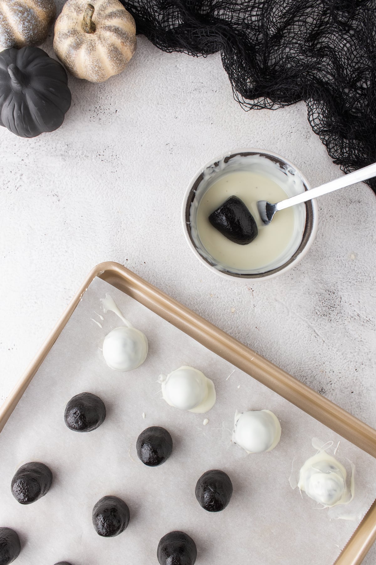 Oreo truffle being dipped in melted white candy coating.
