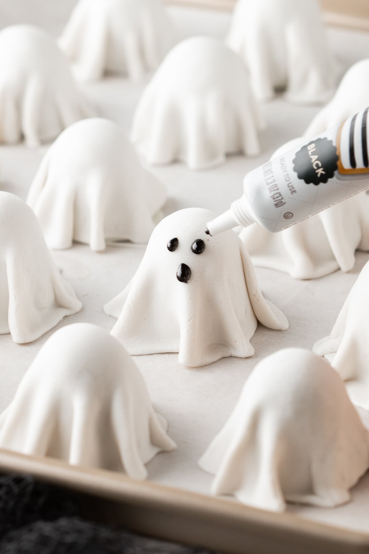 Ghost Oreo Truffles decorated with black icing eyes and mouths.