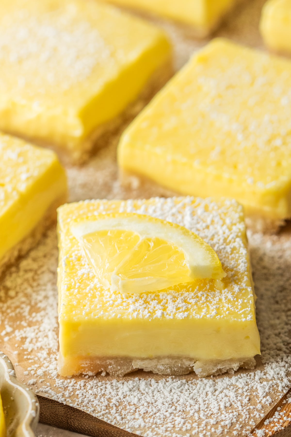 Garnished lemon bars on parchment covered cutting board.