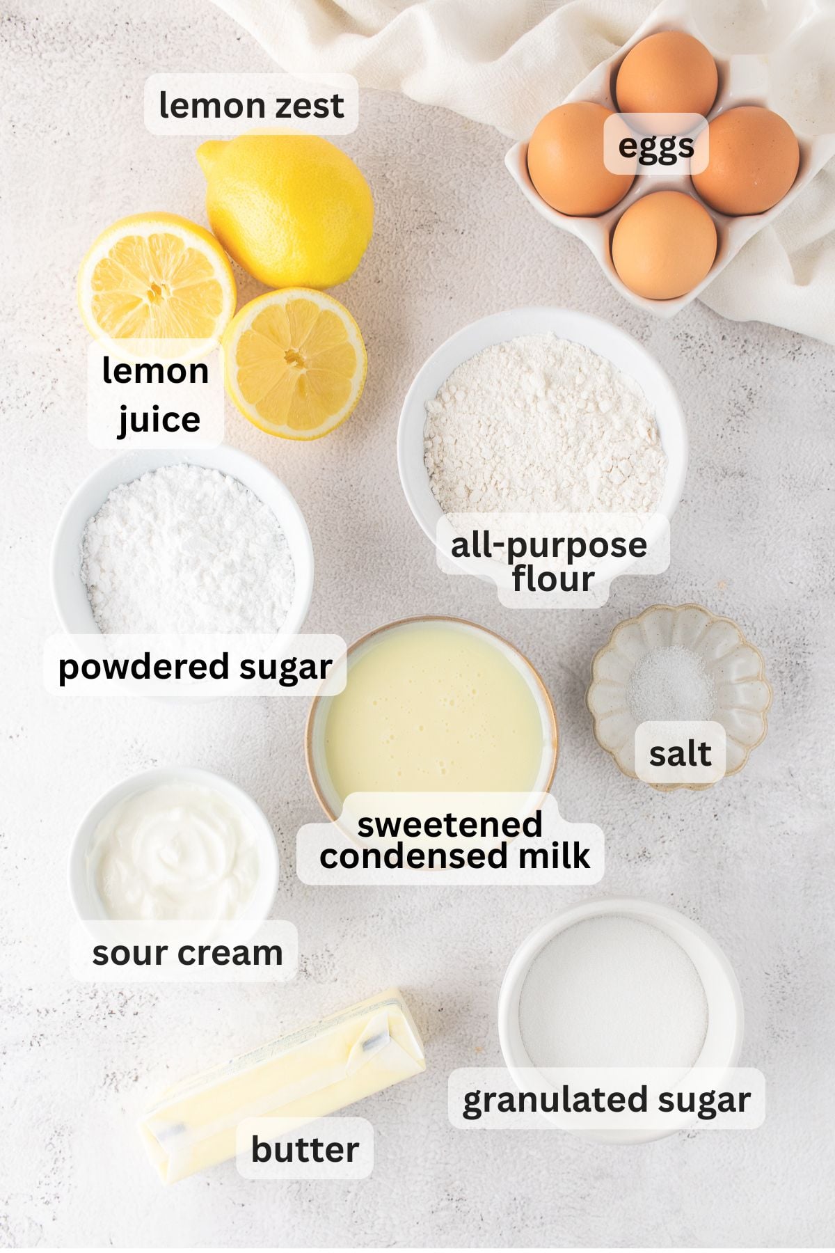 Ingredients for Lemon Bars with Shortbread Cookie Crust arranged in bowls on a table.