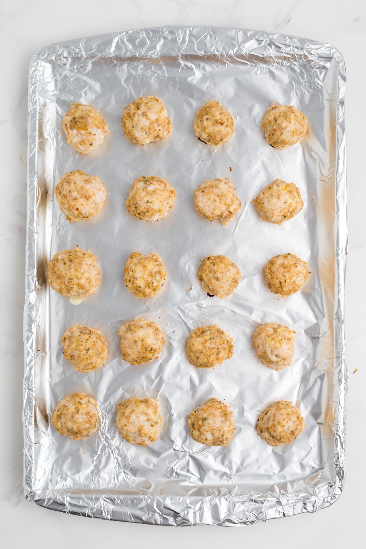 Chicken meatballs arranged on a foil-lined baking sheet after baking.