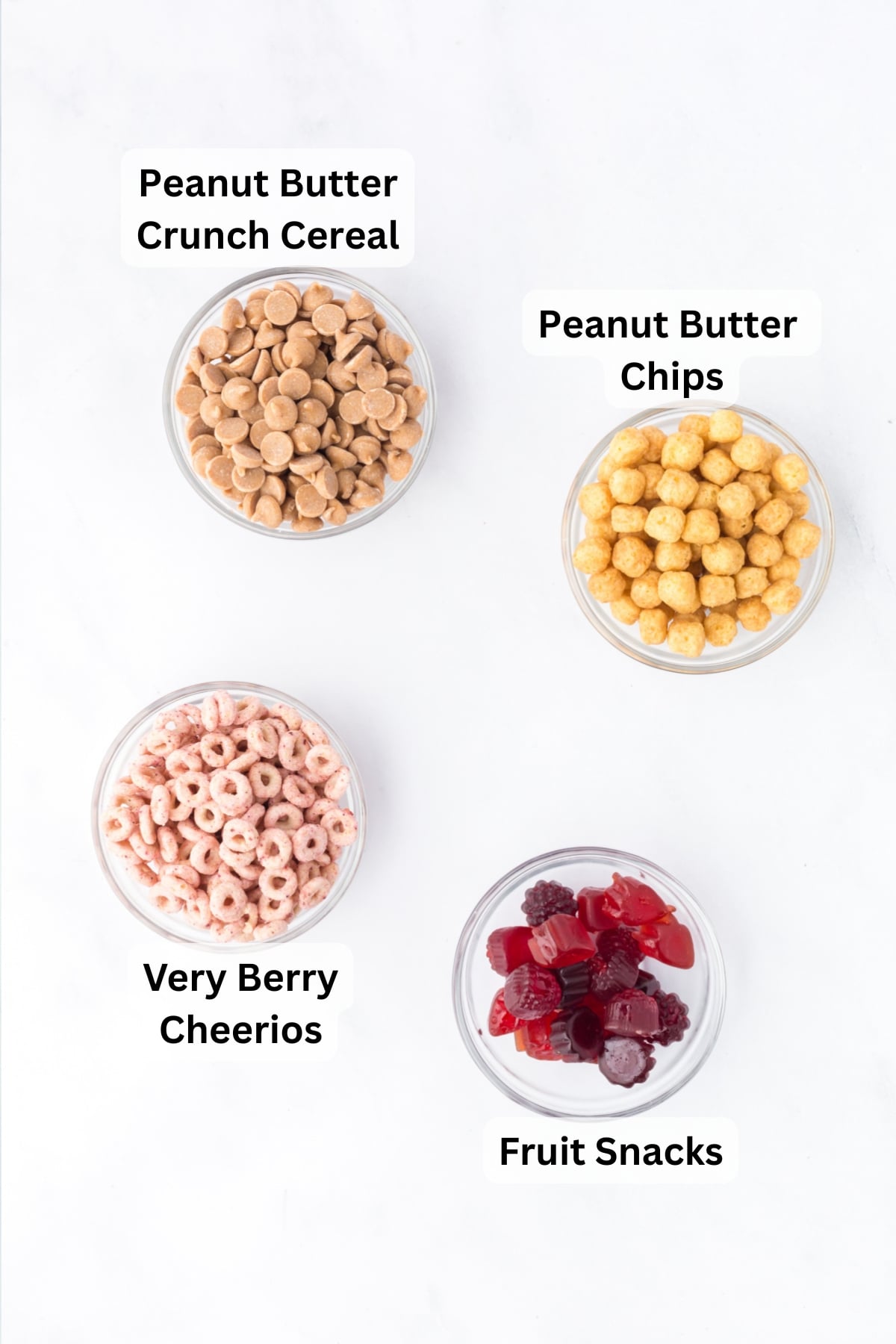 All of the ingredients needed to make PB & J Trail Mix in bowls on a table.