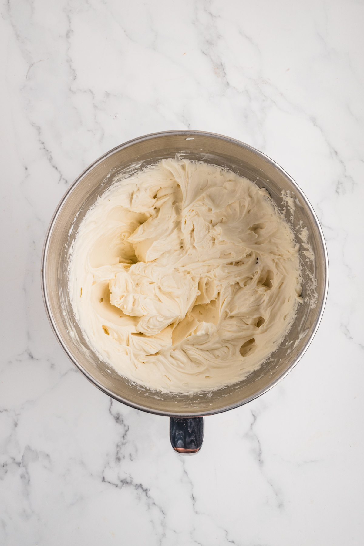 Cream cheese, heavy cream, vanilla, and powdered sugar blended together in a bowl.